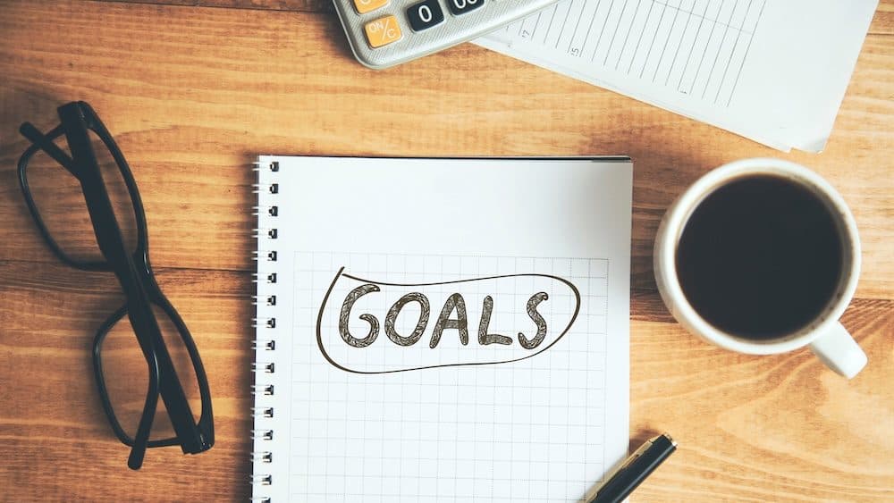 goals text on notepad with coffee